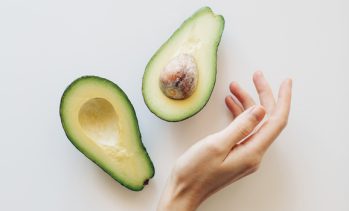 fresh cut avocado with female hand on a white background