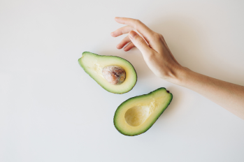 fresh cut avocado with female hand on a white background